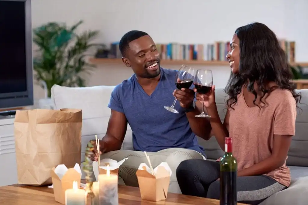 Happy couple enjoying takeout at home while on temporary leave from work.