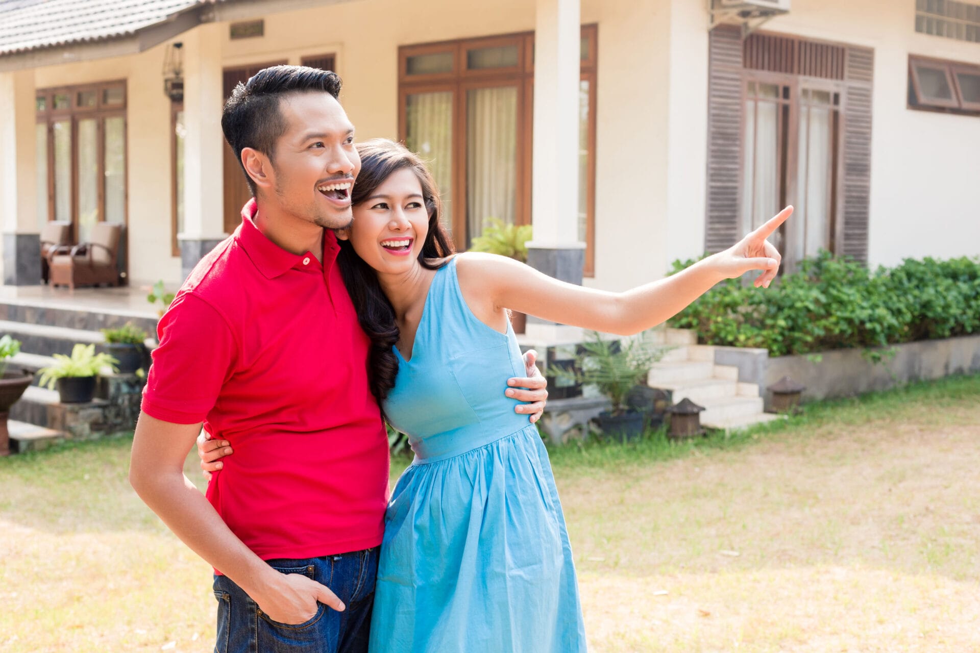 Cheerful young couple looking in the same direction in front of house