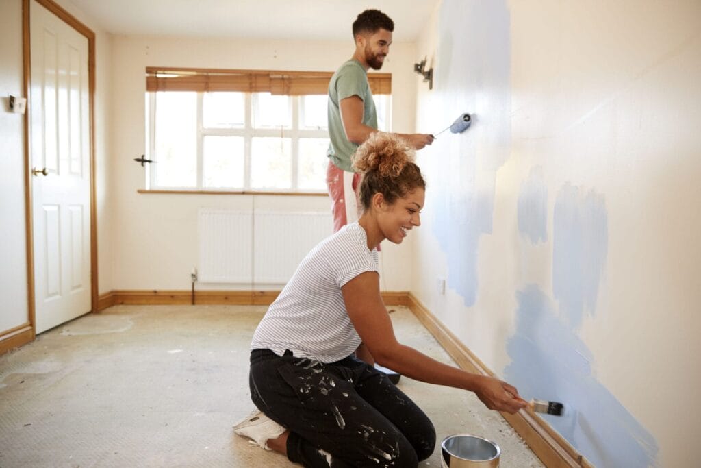 Couple Decorating Room In New Home Painting Wall Together