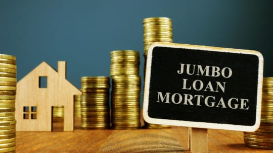 Jumbo Loan mortgage inscription and stacks of coins.