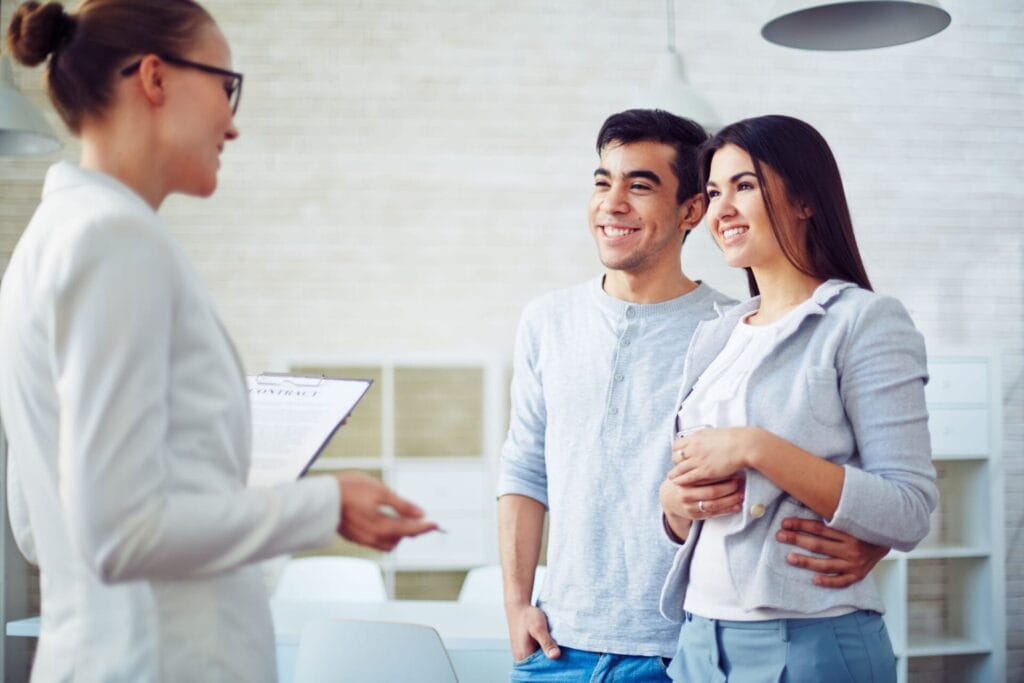 Young couple listening to female agent in realtor office