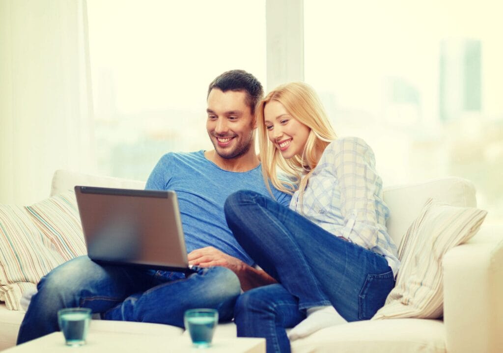love, family, technology, internet and happiness concept - smiling happy couple witl laptop computer at home